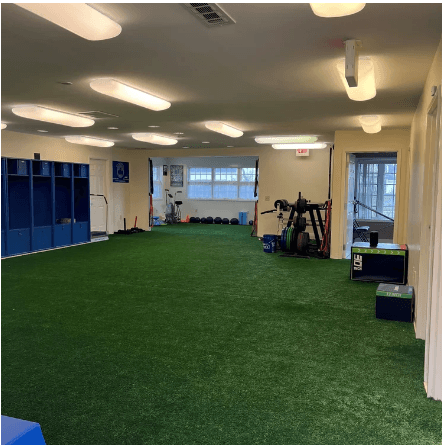 Fleming Athletics indoor training facility with green artificial turf and storage lockers